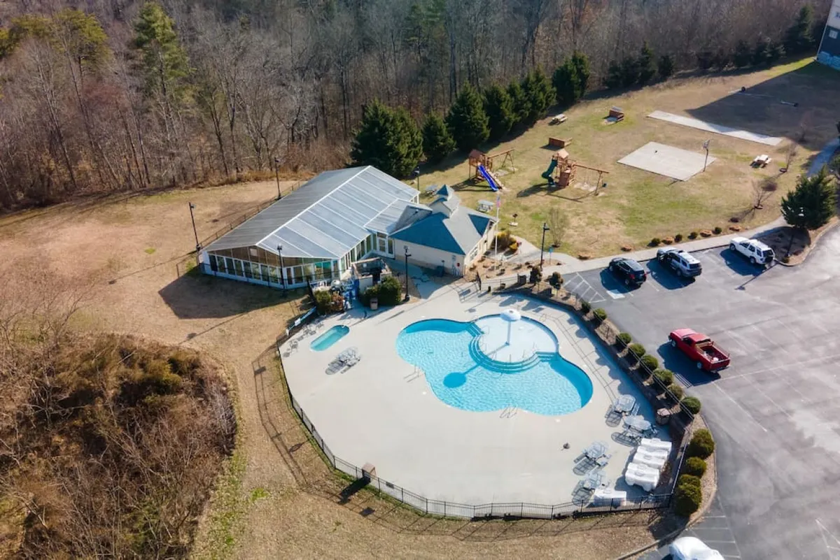 This exterior image features a sparkling outdoor pool, adjacent playground, and clubhouse. The scene is alive with playful energy, showing both family relaxation and areas for children to enjoy outdoor activities.