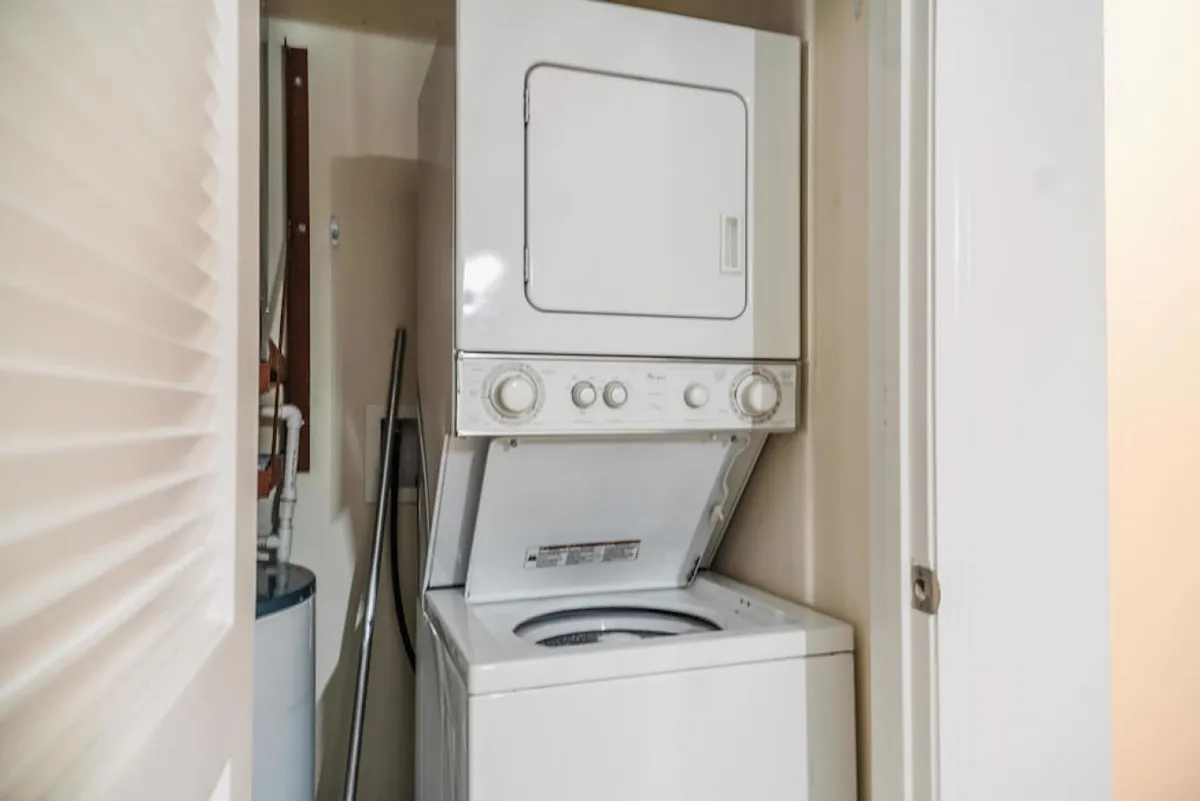 A practical laundry area featuring a stacked washer and dryer along with laundry supplies. The setup is compact and efficient, ensuring laundry tasks are easily managed during any stay.