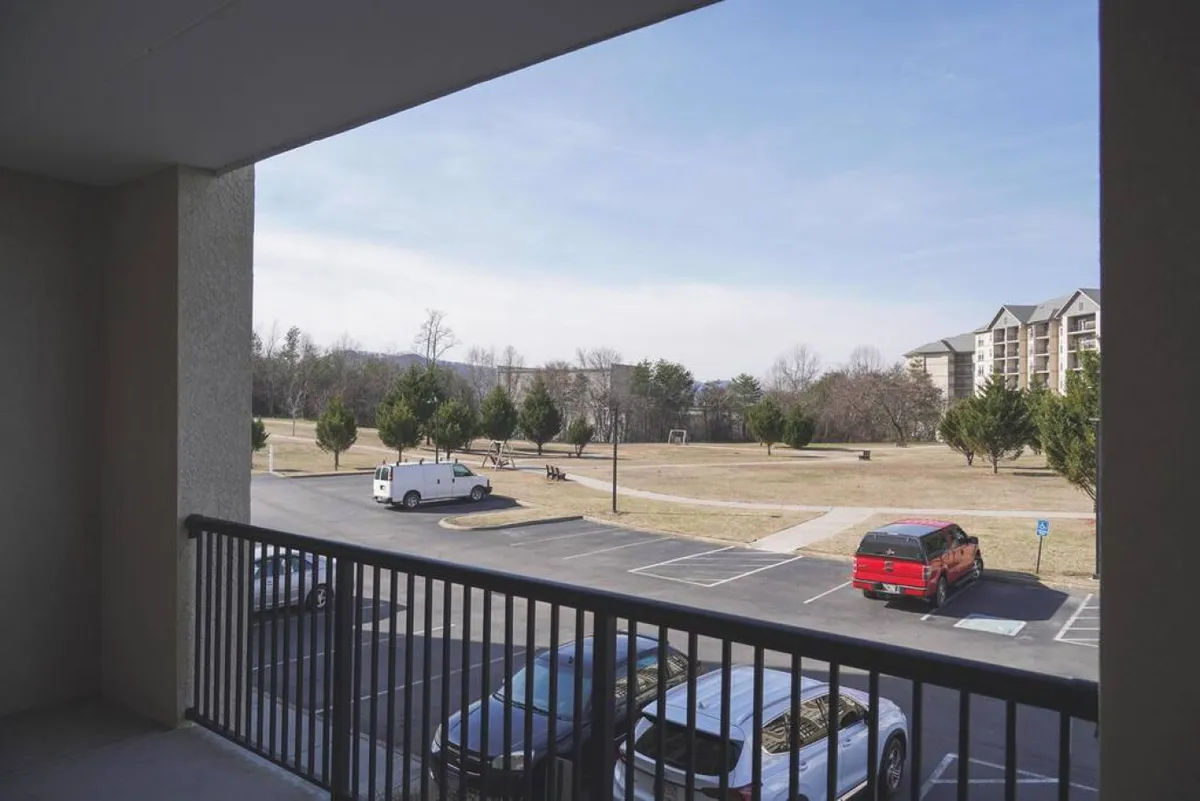 This image provides a view of a wide, grassy area bordered by trees and nearby buildings, with open space suitable for sports, picnics, and casual strolls. The calm, relaxed setting is ideal for outdoor games and gatherings across generations.