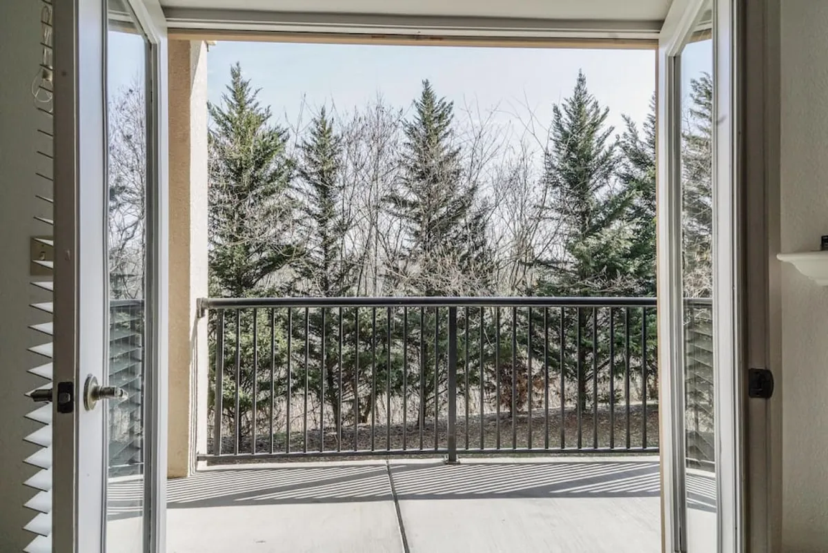 A private balcony with classic railings overlooking abundant greenery, inviting guests to enjoy the fresh air. The space appears serene and ideal for morning coffee, reading, or reflecting while surrounded by nature.